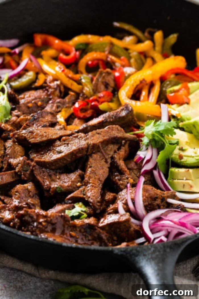 The Ultimate Steak Fajita Marinade 3 Steak fajitas with bell peppers and onions sizzling in a black cast iron skillet, a classic presentation.