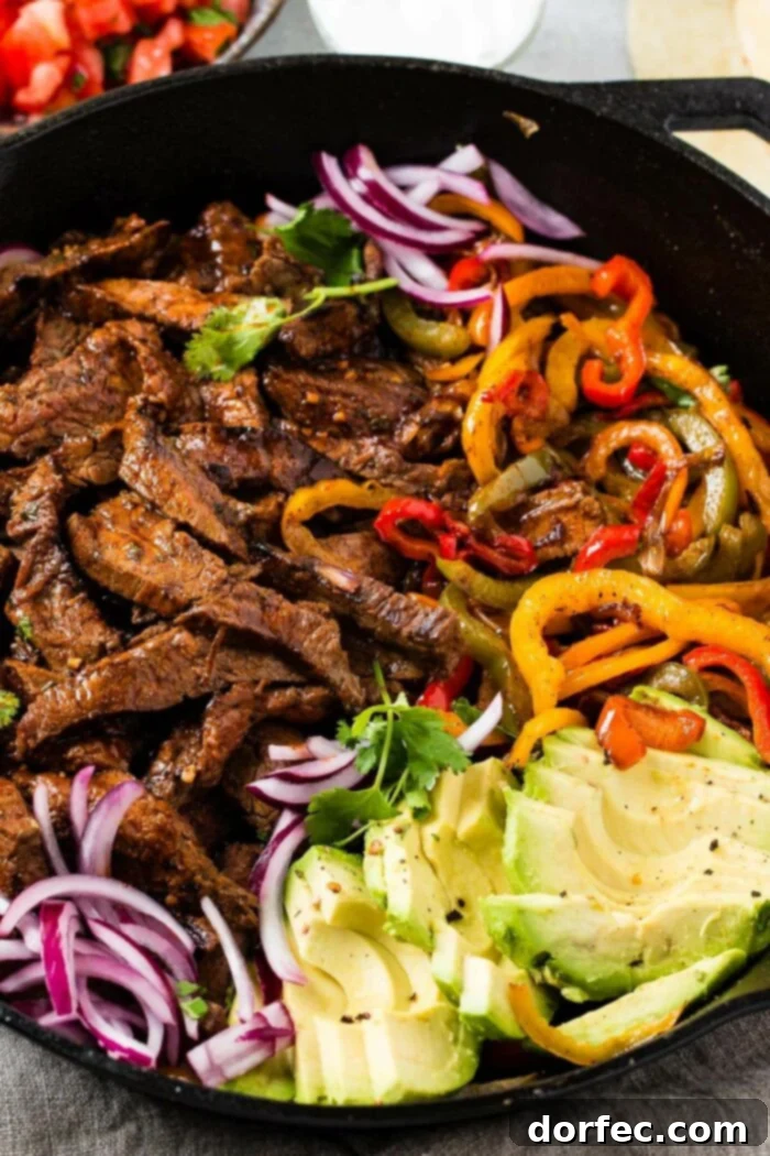 The Ultimate Steak Fajita Marinade 4 Overhead shot of freshly cooked beef fajitas with colorful peppers and onions in a cast iron skillet, ready to be served.