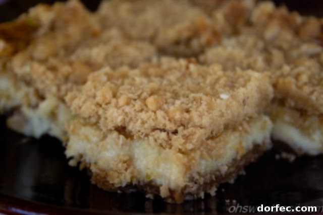 Close-up of a single Key Lime Crumble Bar showing the distinct layers of a golden-brown crumble, creamy lime filling, and a sturdy crust.