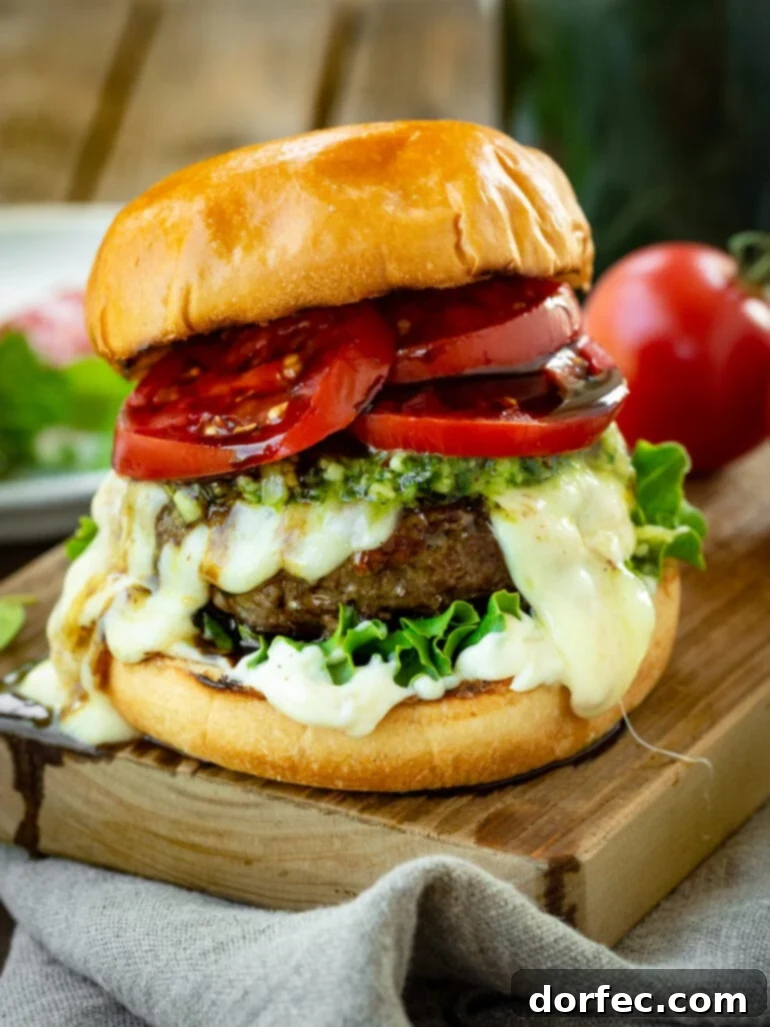 a photo of a juicy pesto burger on a toasted brioche bun topped with melted havarti cheese, pesto, lettuce, garlic aioli and tomato slices drizzled with a balsamic glaze.