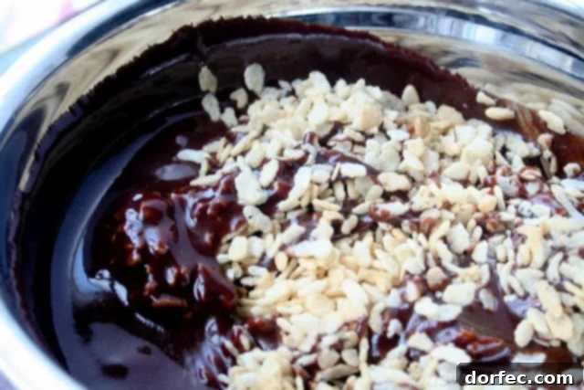 Freshly mixed Milky Way Krispies, still warm in the bowl, showing visible chunks of candy and glossy Nutella coating.