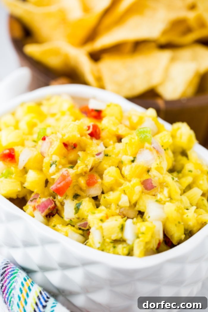 A beautifully presented white pineapple dish filled with fresh pineapple salsa, featuring diced peppers, cilantro, and red onions.