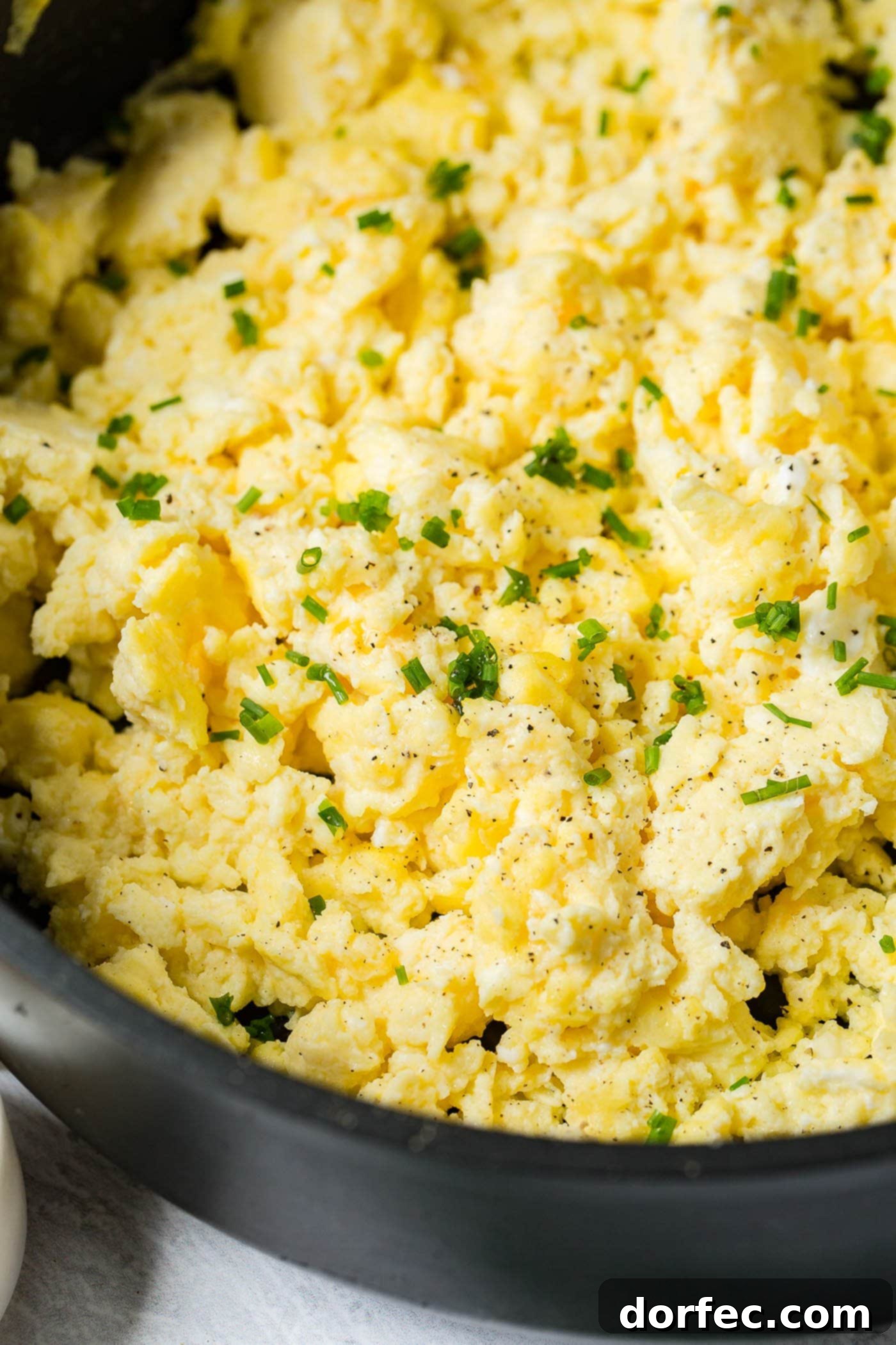 Fluffy Scrambled Eggs Detail A close-up of perfectly scrambled eggs, garnished with fresh sliced green onion, showcasing their fluffy and moist texture.