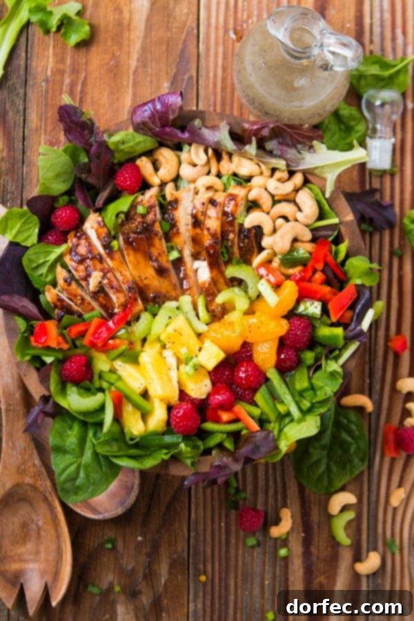 A simple yet elegant teriyaki chicken salad with mixed greens, colorful fresh fruits, and tender chicken, beautifully arranged and ready to be topped with a delicious dressing.