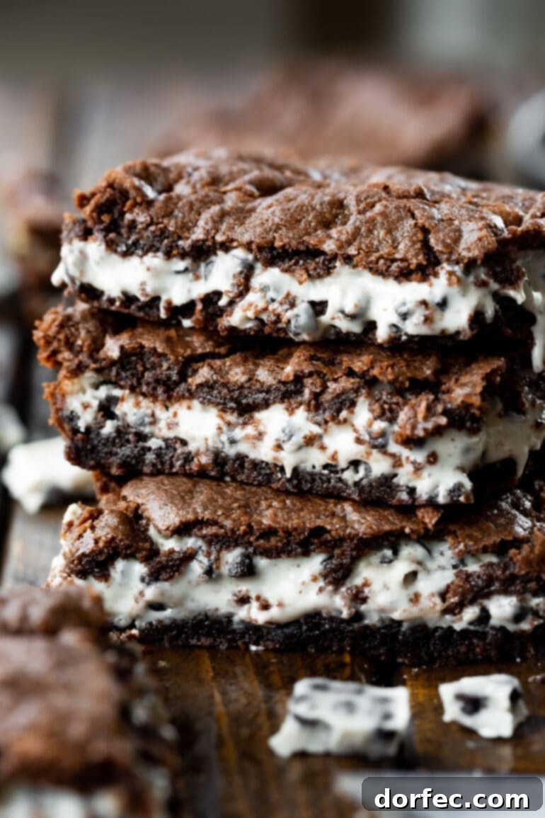 A photo of three cookies and cream brownies stacked on top of each other, showcasing the distinct layers: brownie bottom, creamy white chocolate middle, and a brownie top.