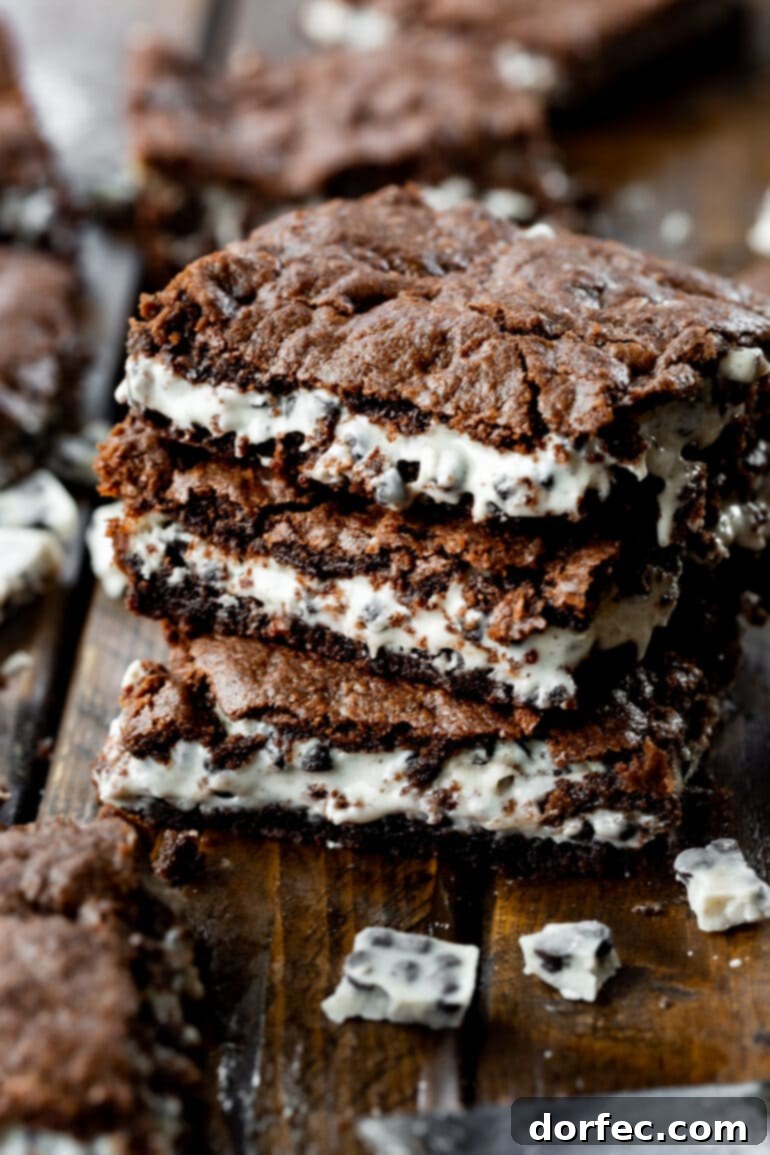 A photo of three cookies and cream brownies stacked on top of each other, displaying their rich brown and white layers.