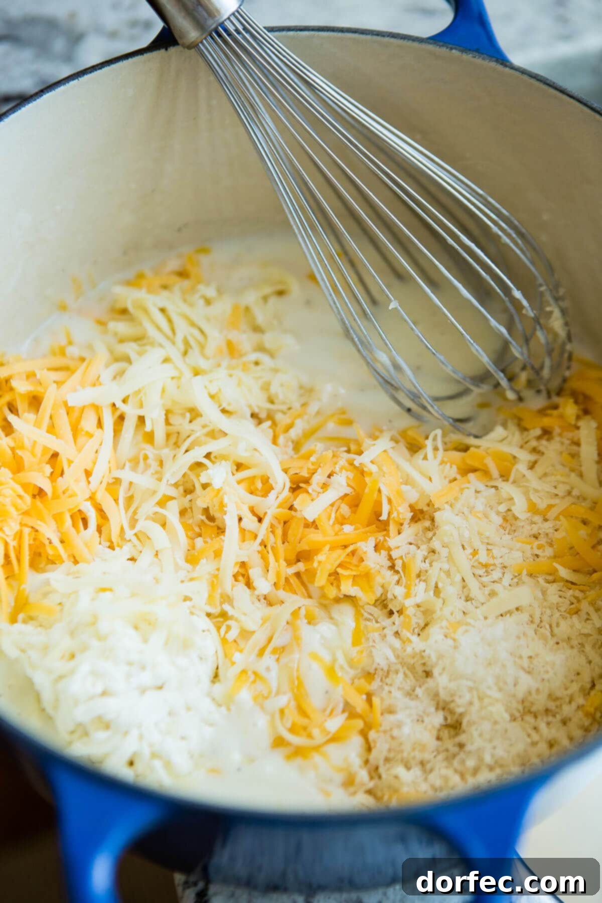 Loaded Chicken Bacon Ranch Macaroni and Cheese 3 Three kinds of cheese and milk in a Dutch oven with a whisk, ready to be transformed into a rich sauce