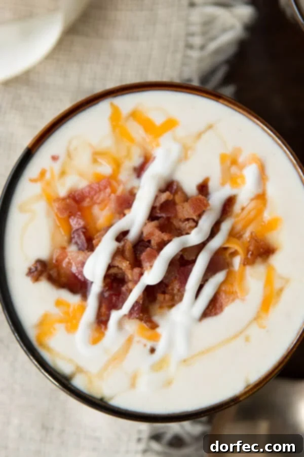 Creamy golden loaded baked potato soup, garnished with bacon, cheese, and a secret drizzle