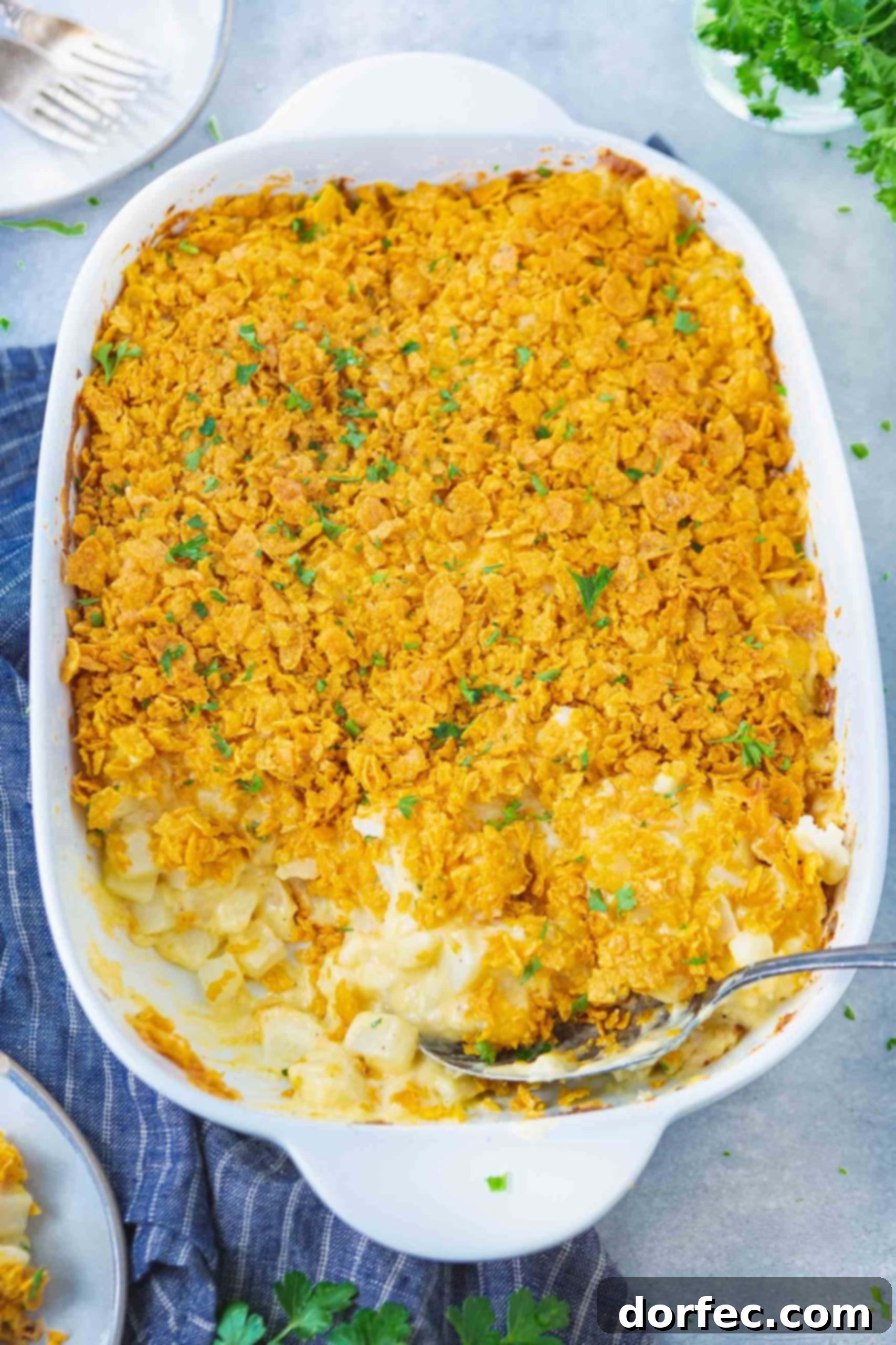 A casserole dish filled with creamy Funeral Potatoes, a few servings already removed, showcasing the rich, cheesy interior.