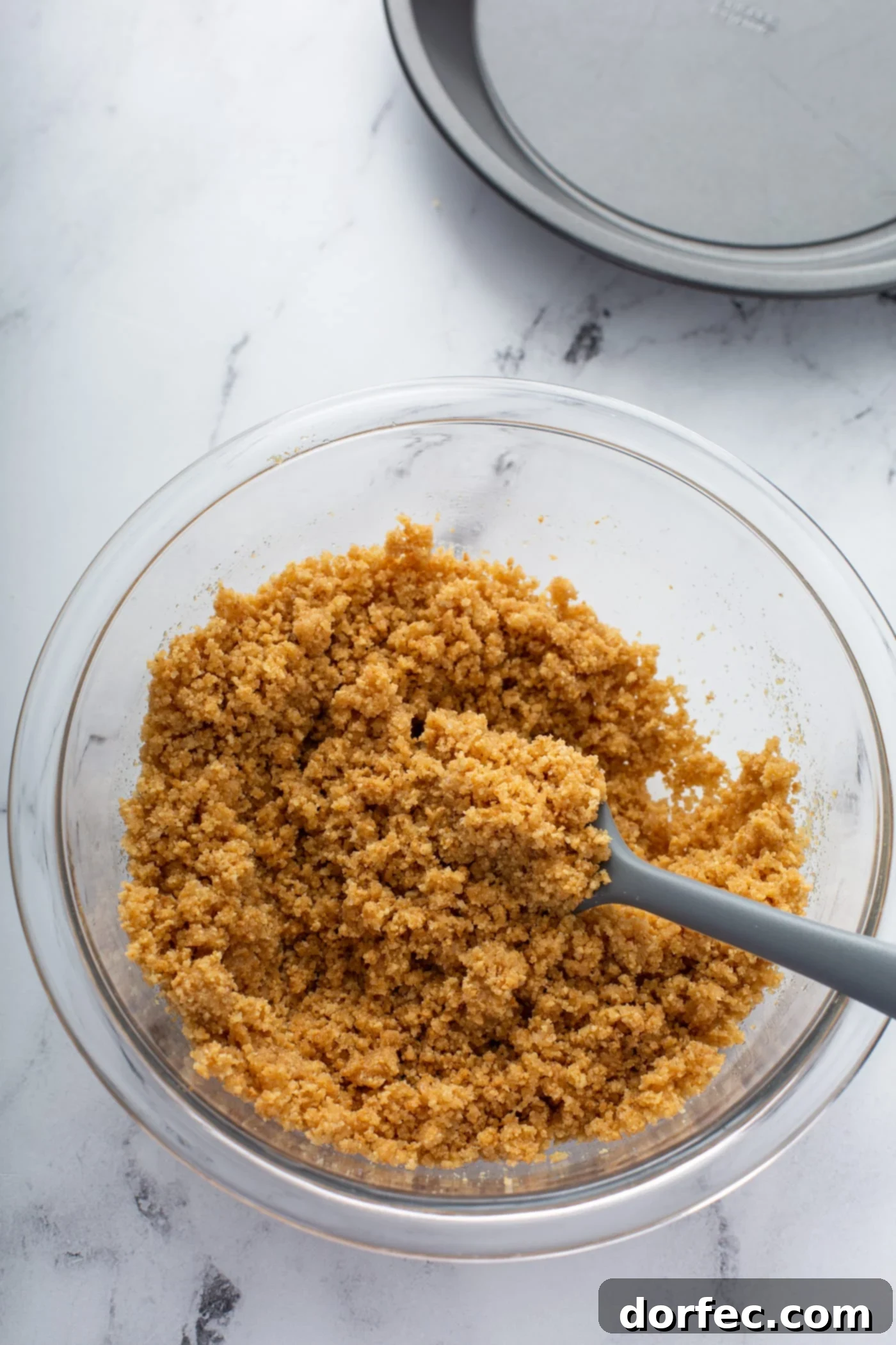 Decadent Dulce De Leche Banana Cream Pie 3 Crushed graham cracker crumbs and melted butter being stirred together in a bowl.