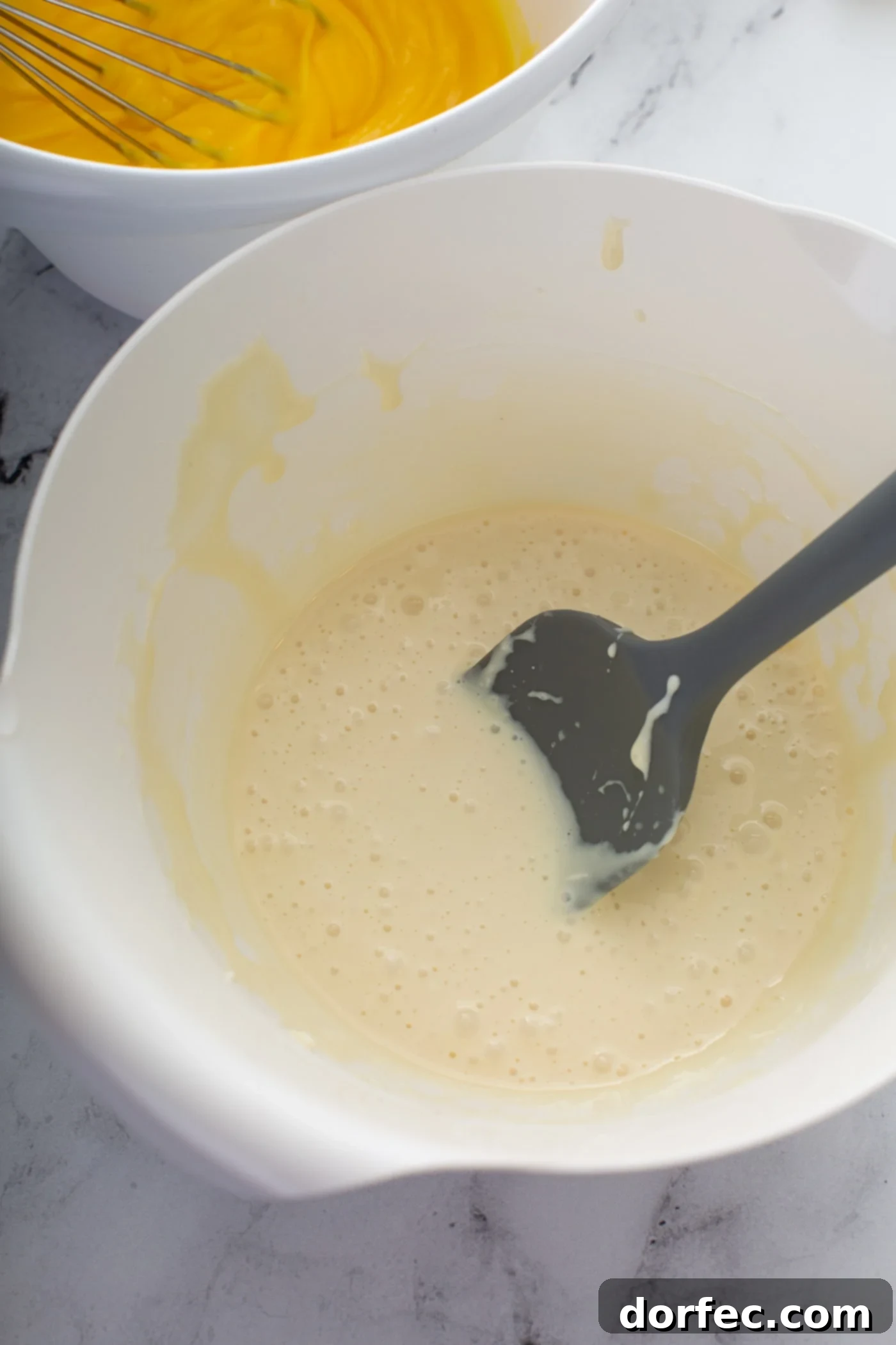 Decadent Dulce De Leche Banana Cream Pie 9 Cream cheese and sweetened condensed milk being mixed together in a mixing bowl.
