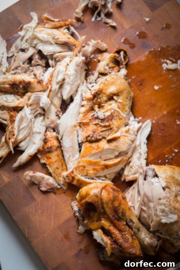 This is the easiest way to enjoy a juicy, rotisserie-like chicken by only using a crockpot. Slow cooker whole chicken that anyone can make! Delicious shredded slow cooker whole chicken meat, ideal for various meals, served on a wooden board.