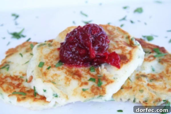 Crispy Mashed Potato Pancakes served on a white plate with a side of vibrant cranberry chutney.