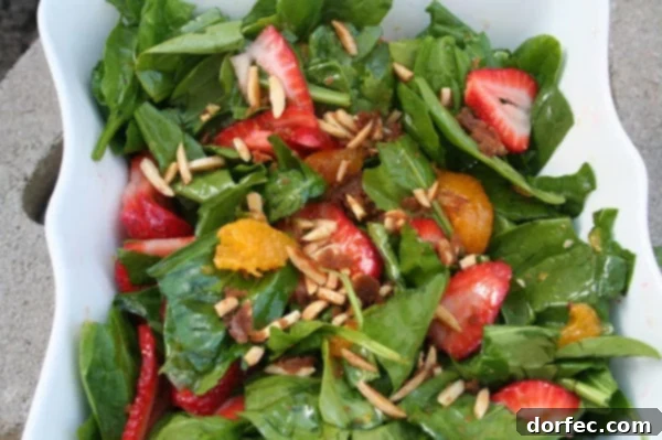 A vibrant and colorful Thanksgiving salad featuring fresh greens, fruit, nuts, and a light dressing, presented in a large serving bowl.