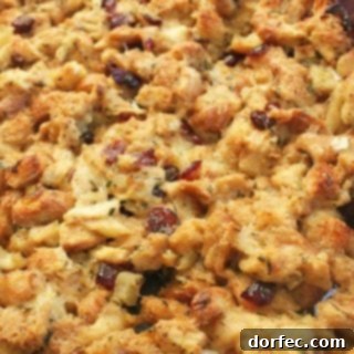 A top-down view of Apple Cranberry Stuffing in a square baking dish, showcasing its golden crust and vibrant ingredients.