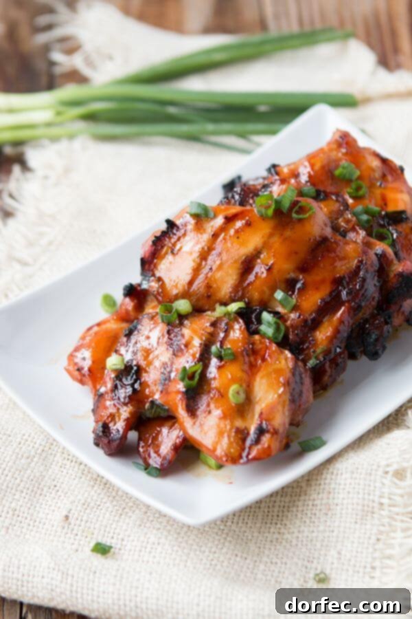 A serving of Grilled Hawaiian Chicken, generously drizzled with extra marinade, next to a portion of creamy coconut rice and a colorful side salad.