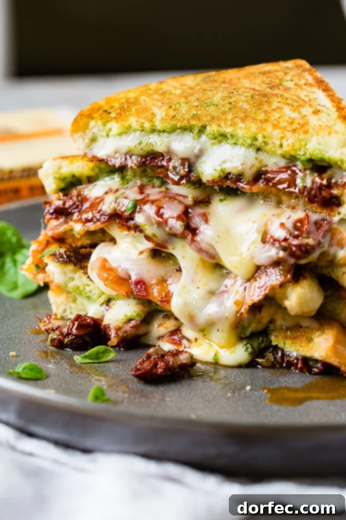 Multiple sun dried tomato bacon pesto grilled cheese sandwiches stacked and ready