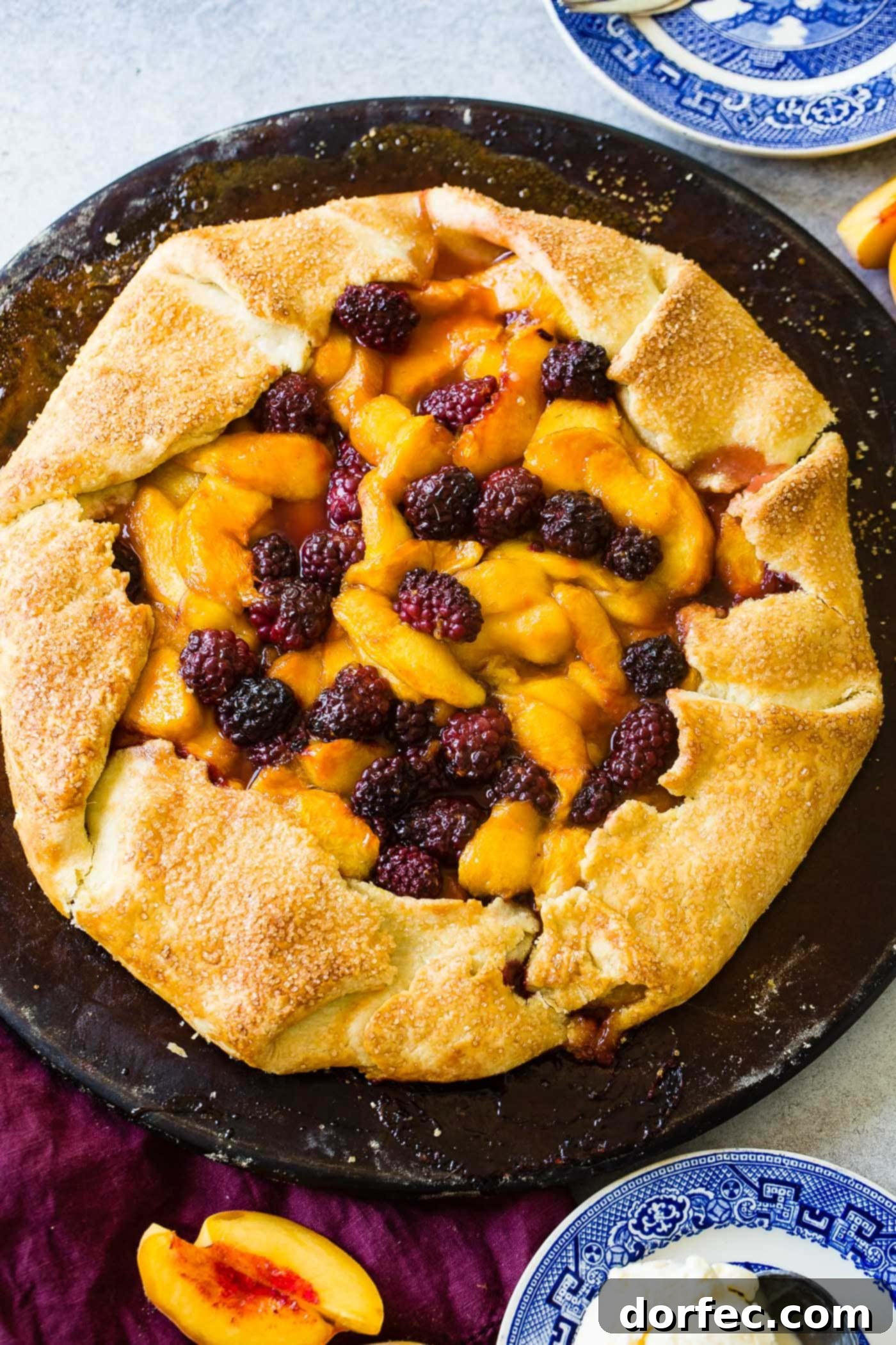 A closer look at a section of the rustic peach blackberry galette, showing the golden, crimped crust and the vibrant fruit filling, baked to perfection.