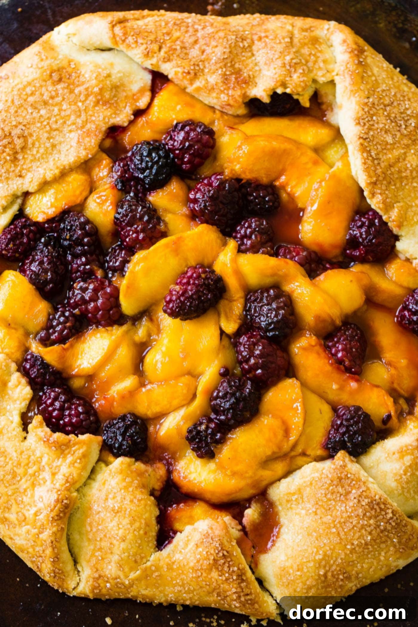 Overhead shot of a rustic peach blackberry galette with a flaky, golden crust. The fruit filling is a vibrant mix of peaches and blackberries, showcasing the simple, elegant design.