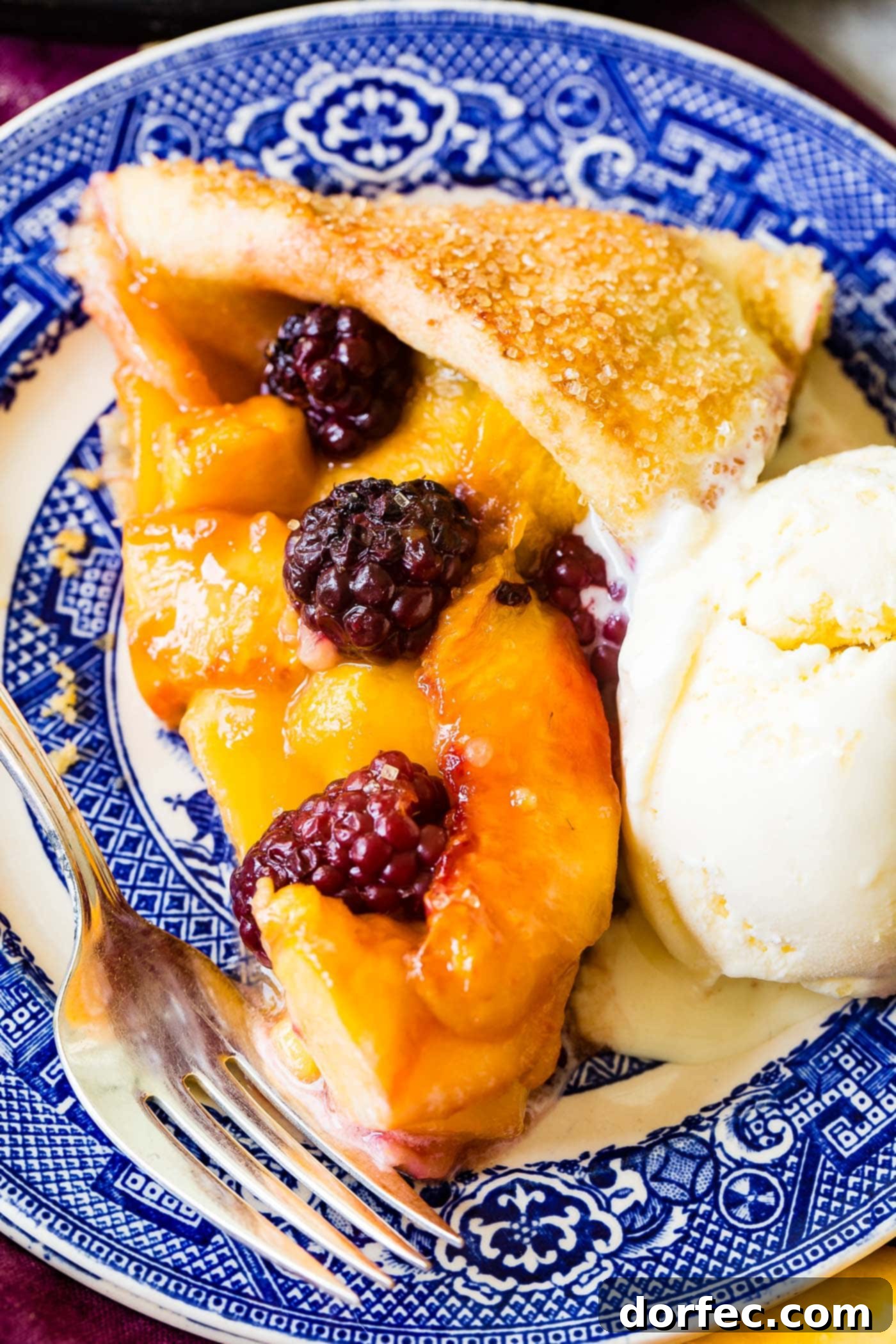 A delicious slice of peach blackberry galette, served warm on a plate, highlighting the perfectly baked crust and the enticing fruit filling.