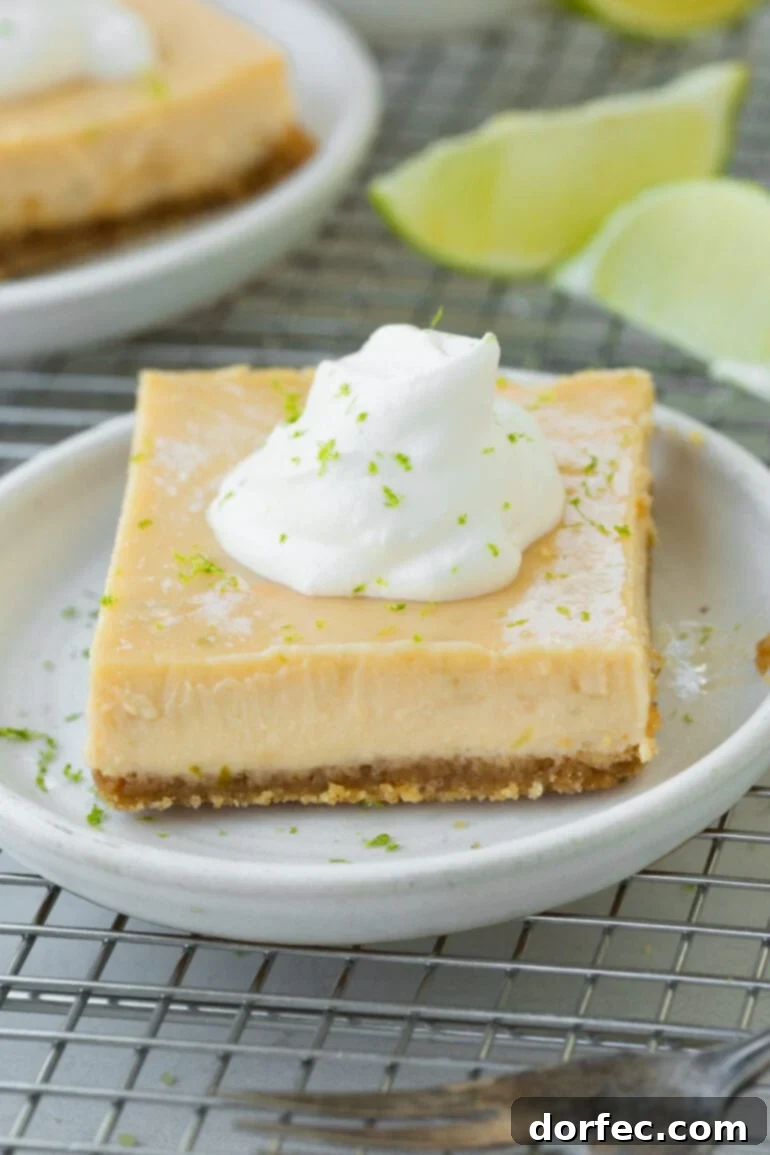 Key Lime Pie Bars 2 A photo of one key lime pie bar sitting on a small dessert plate, topped with a dollop of whipped cream and sprinkled with lime zest.