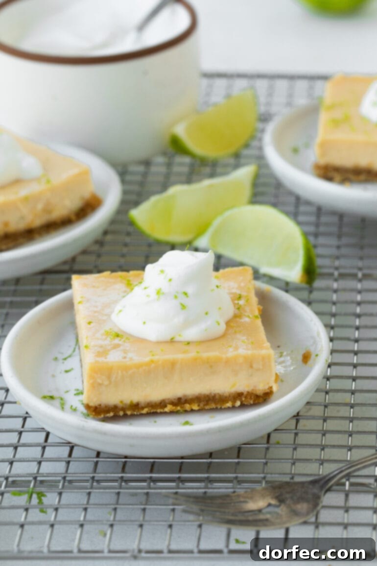 Key Lime Pie Bars 4 A photo of a small dessert plate topped with a key lime bar with lime wedges scattered around it and other plates of dessert in the background.