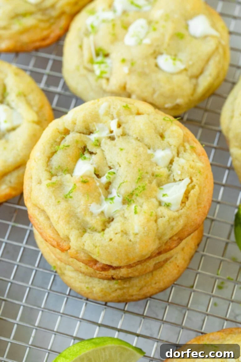 a photo of a stack of 4 white chocolate lime cookies baked until golden sitting on a wire cooling rack and surrounded by other cookies