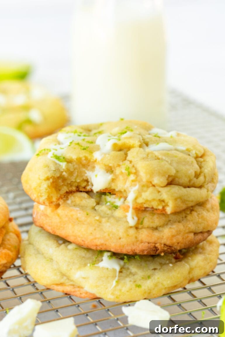 a photo of a stack of golden baked key lime cookies loaded with white chocolate chunks with a bite taken out of the top cookie