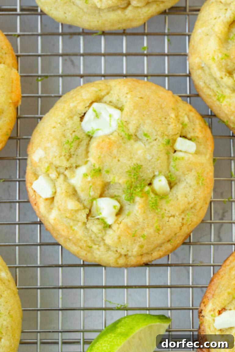a photo of a golden baked cookies full of creamy white chocolate chunks and topped with lime zest.