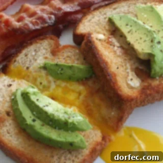 California Toad in a Hole, a wholesome breakfast featuring an egg baked into bread, topped with fresh avocado and served with bacon.