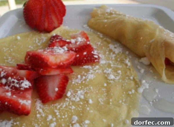Sunny Citrus Crepes 2 Delicious lemon crepes on a plate with fresh berries and lemon syrup.