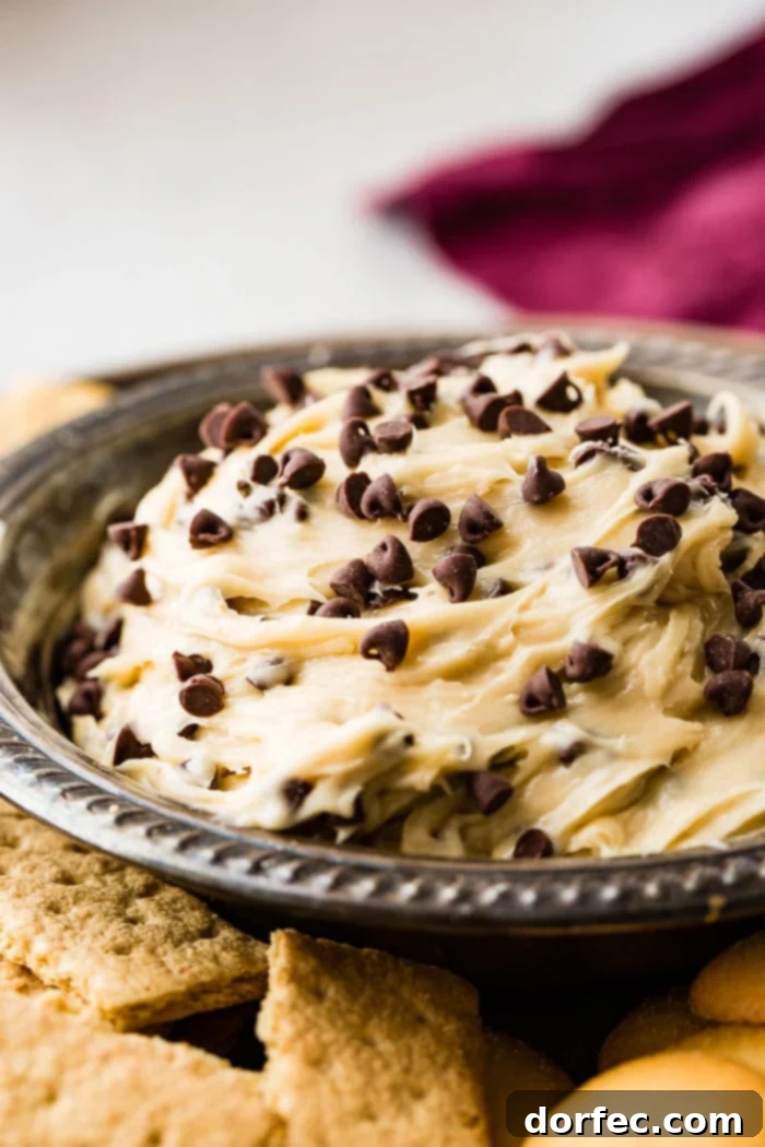 Edible Chocolate Chip Cookie Dough Dip 4 A close-up of a metal bowl brimming with homemade easy chocolate chip cookie dough dip, showcasing its creamy texture and visible chocolate chips.