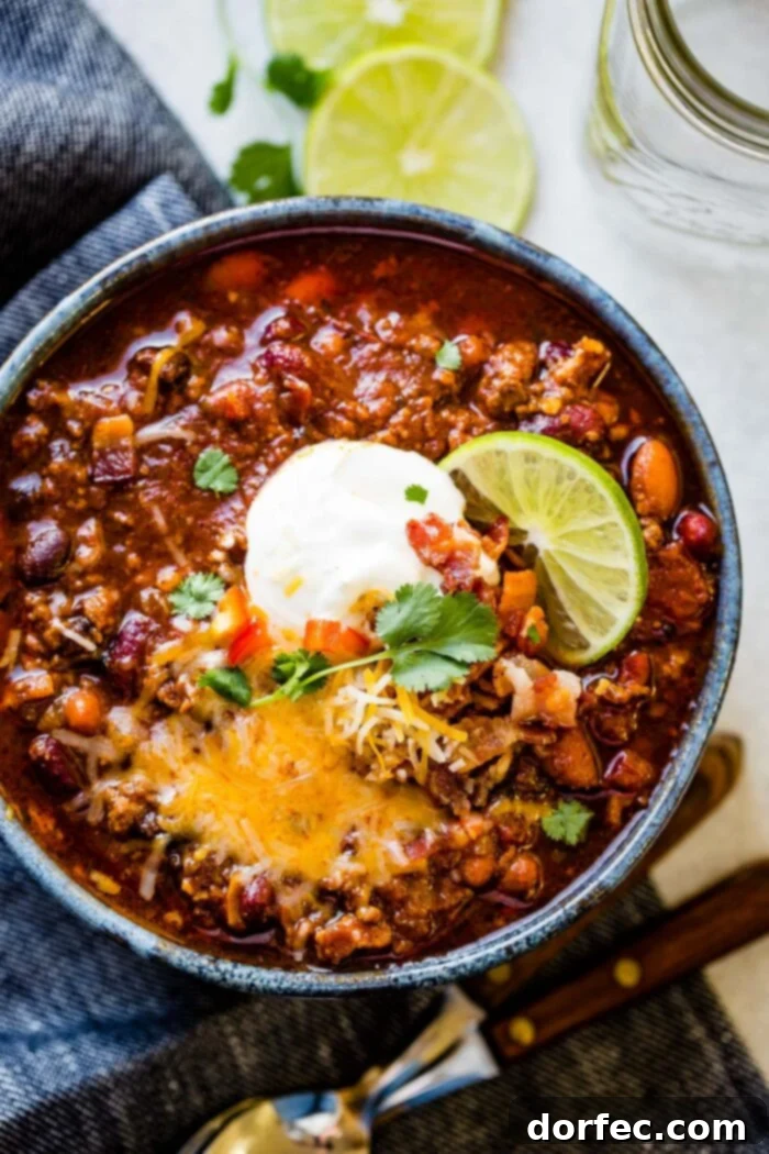 Championship Instant Pot Chili 6 a photo of a large bowl full of chili topped with cheese, sour cream, cilantro, bacon bits and a slice of fresh lime.