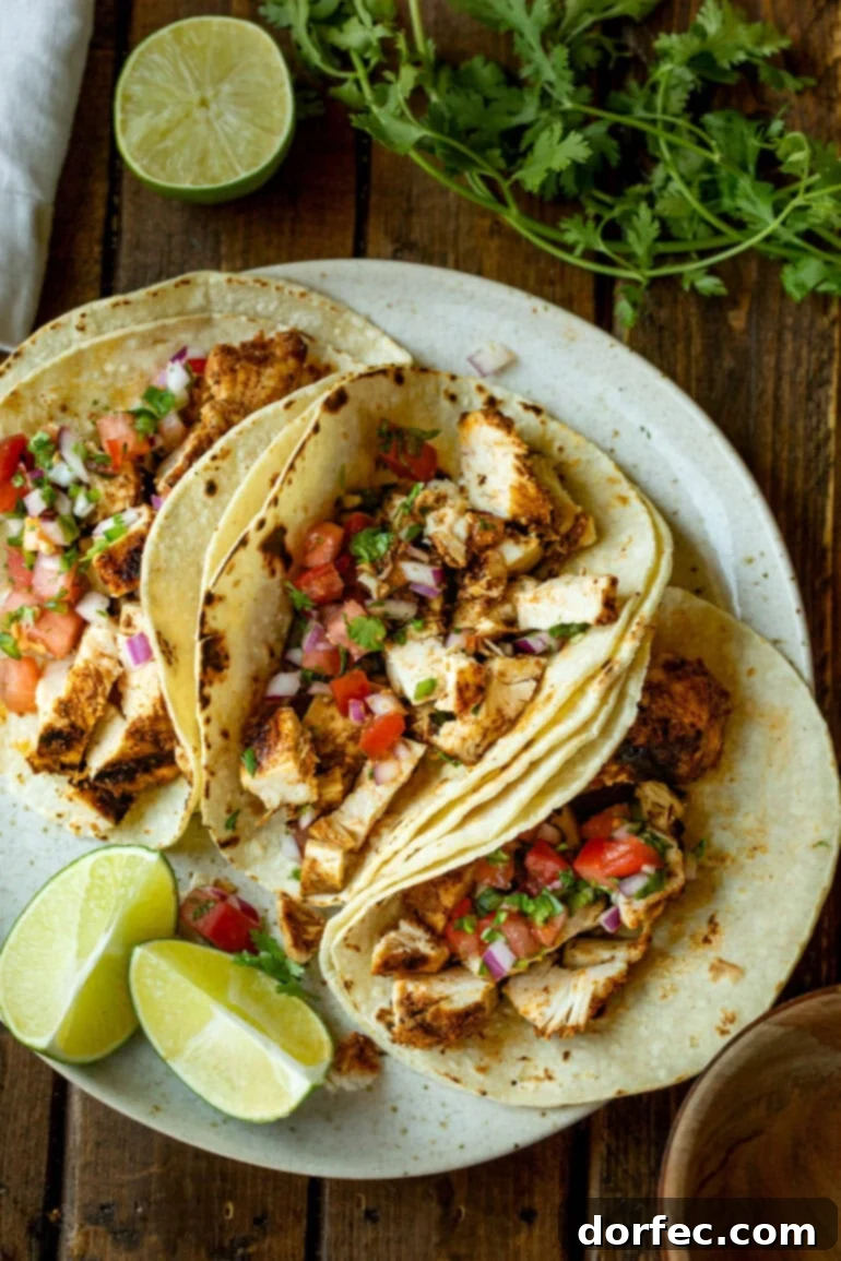 a photo of a several grilled chicken tacos in corn tortillas topped with pico de gallo
