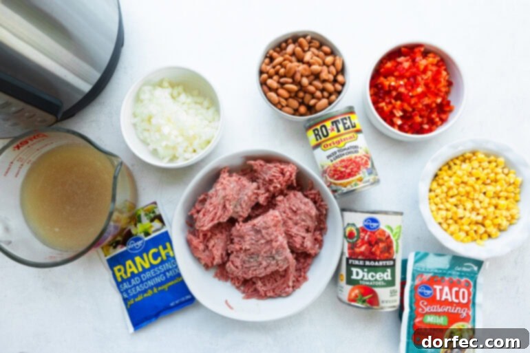 all the ingredients for instant pot taco soup including ground beef, Rotel, pinto beans, cans of diced tomatoes, ranch seasoning powder, diced onions and diced red bell pepper