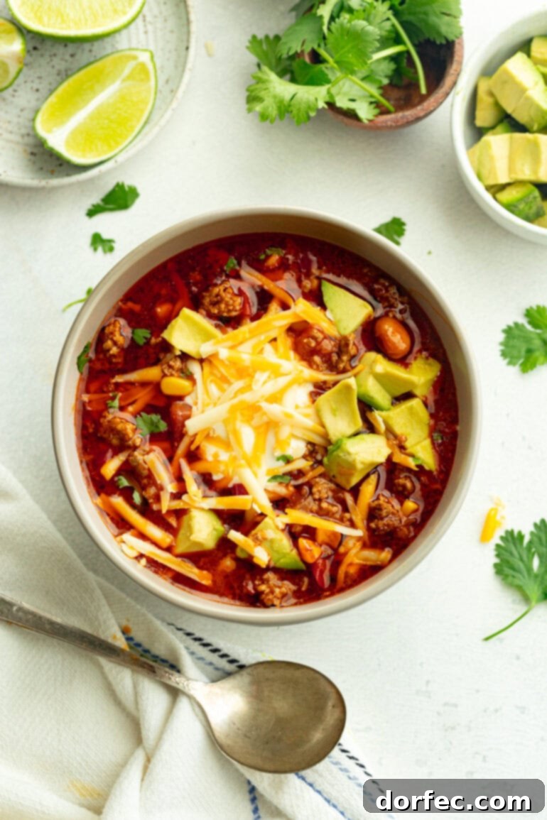 Grey bowl filled with mexican sopa, finished with fresh cilantro, creamy sour cream, shredded cheese, and avocado pieces.