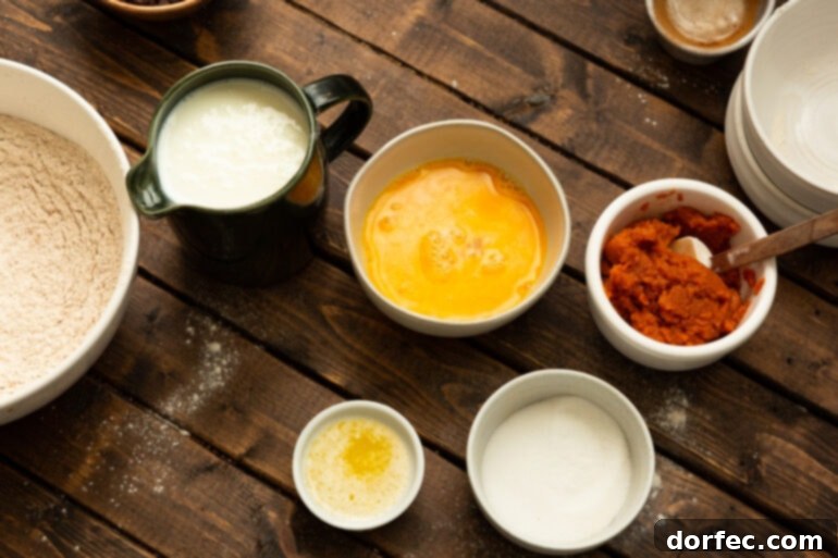 A collection of small containers holding the wet ingredients for whole wheat pumpkin pancakes, including buttermilk, eggs, pumpkin puree, and melted butter, neatly arranged for cooking.