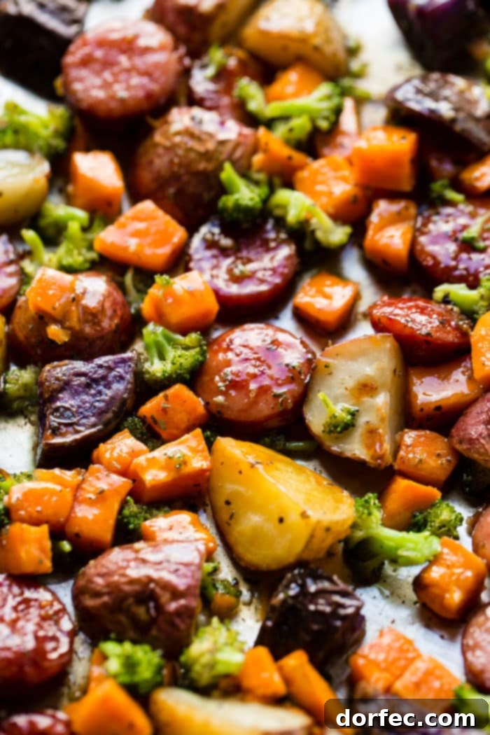 Freshly roasted honey garlic kielbasa and root vegetables beautifully arranged on a sheet pan, ready to eat