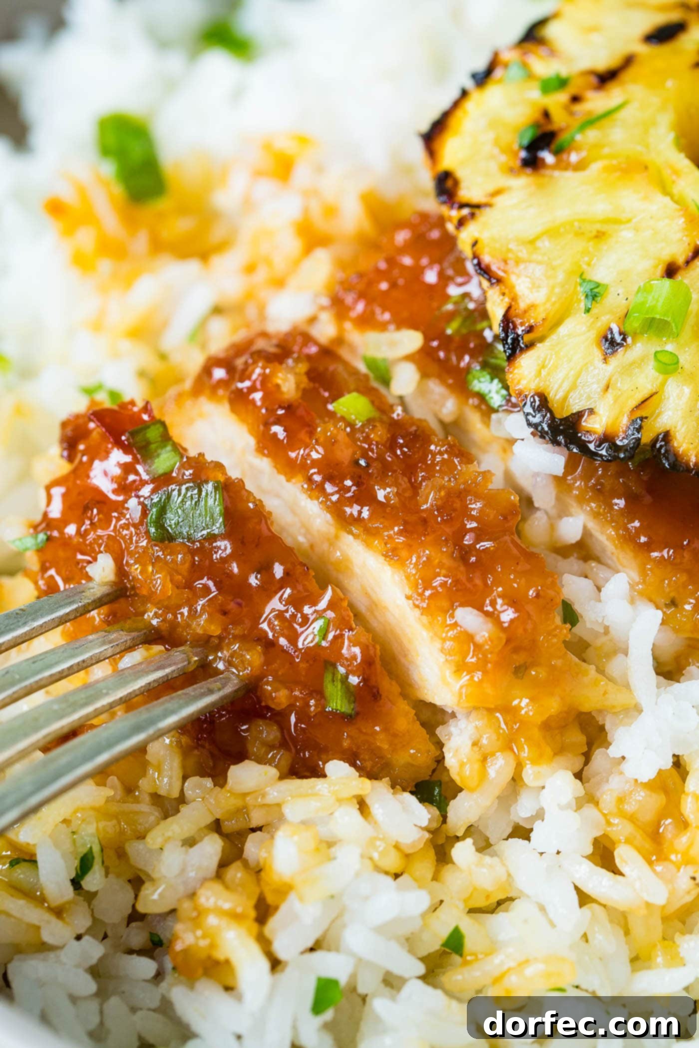 Sweet and Sticky Pineapple Chicken Dinner 4 Several pieces of golden breaded chicken covered in a sticky sweet and sour glaze, ready for serving or further preparation, highlighted by a bright green garnish.
