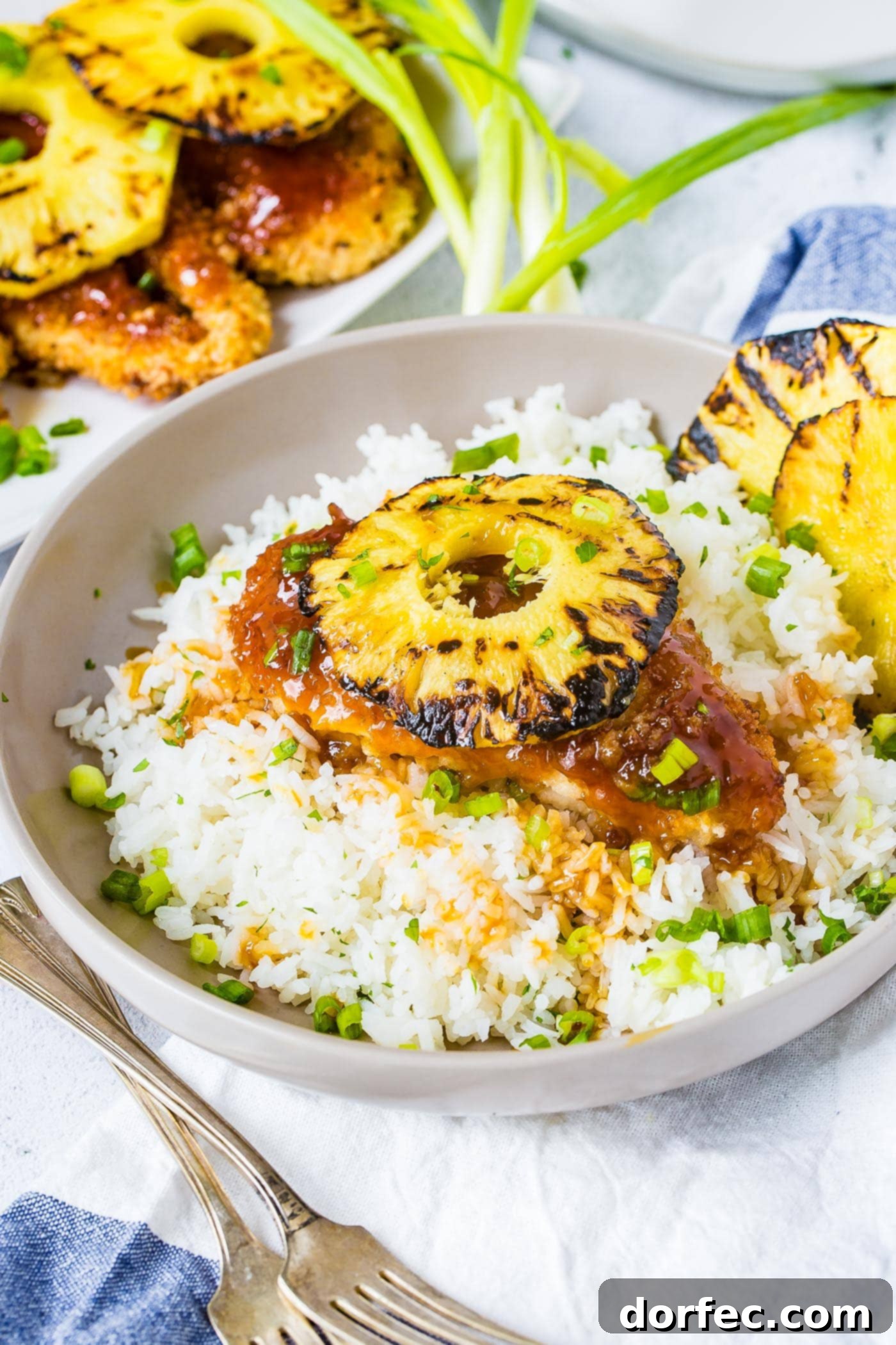 Sweet and Sticky Pineapple Chicken Dinner 5 A vibrant and inviting bowl of white rice, topped with breaded sweet and sour chicken, and a slice of perfectly grilled pineapple, demonstrating a quick and tasty dinner option.