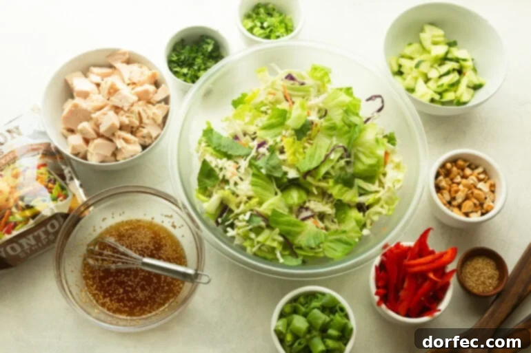 All the fresh ingredients for Wonton Chinese Chicken Salad laid out in separate small bowls, showcasing vibrant colors and textures before assembly.