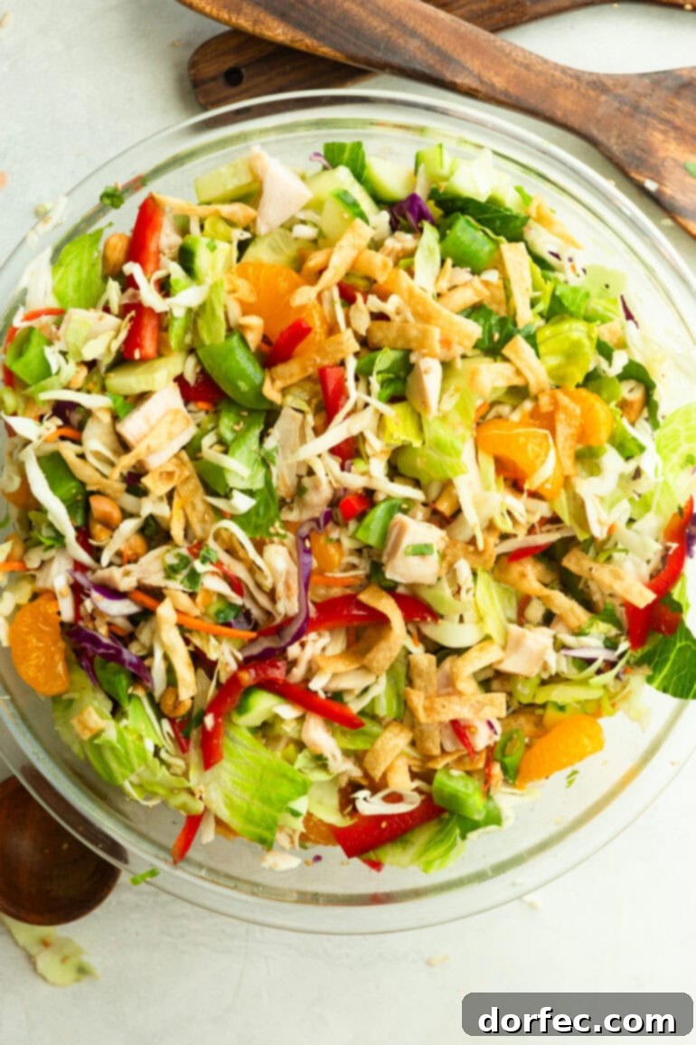A large glass bowl overflowing with beautifully tossed Wonton Chinese Chicken Salad, featuring visible wonton strips and mandarin oranges, inviting you to dig in.