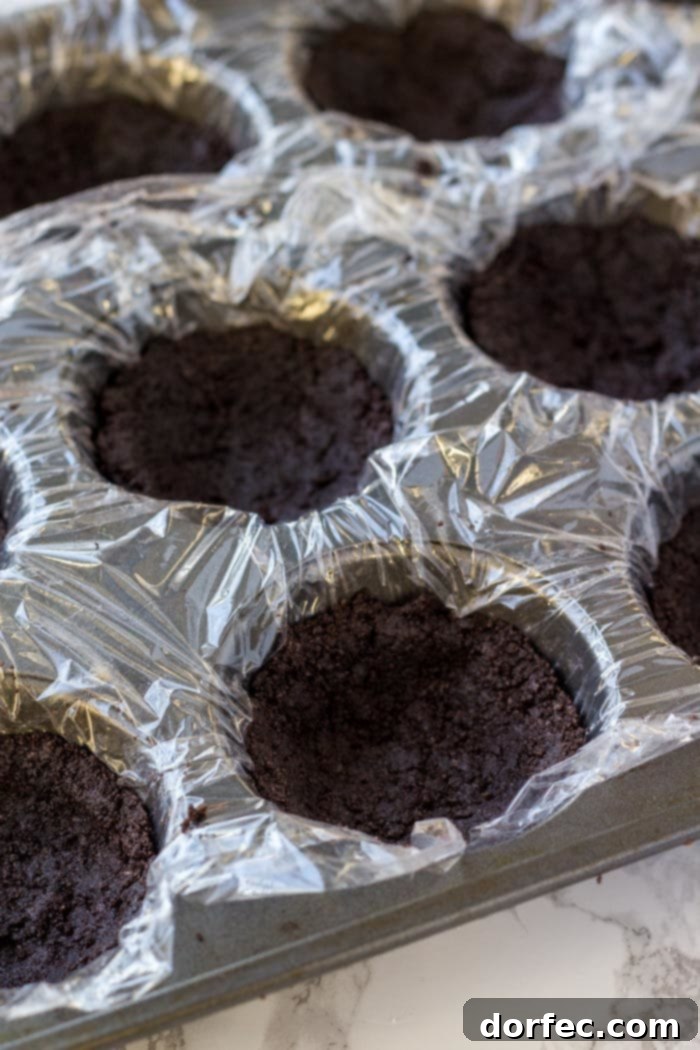Effortless Chocolate Cheesecake Bites 4 Muffin tin with an Oreo cookie crust, perfectly pressed into individual wells, ready for the chocolate cheesecake filling.