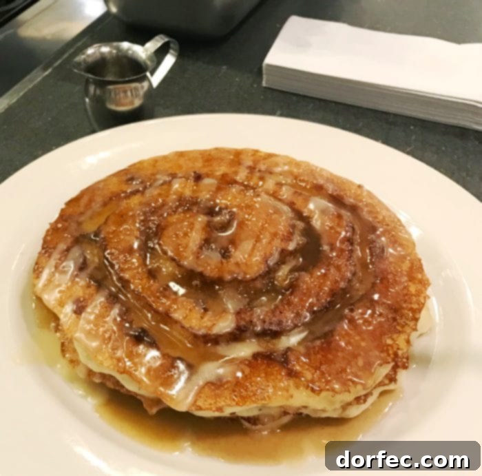 A close-up of a Cinnamon Roll Pancake, emphasizing its delicious icing and impressive size, perfect for brunch.