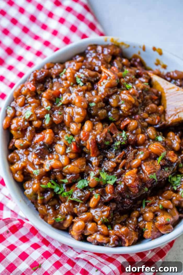 Old-Fashioned Homemade Baked Beans 4 A white bowl full of saucy baked beans with chopped cilantro sitting on a red checkered napkin