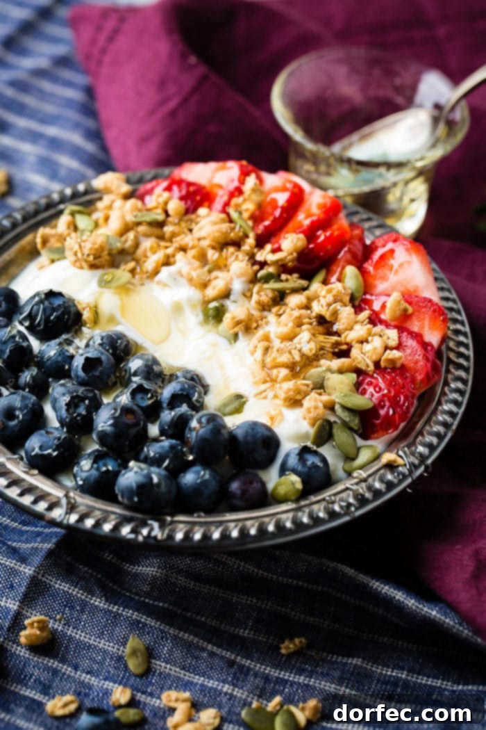 Creamy Instant Pot Yogurt 2 Bowl of instant pot yogurt with fresh blueberries, strawberries, pepitas, granola and a drizzle of honey in a vintage bowl with blue and purple napkins.