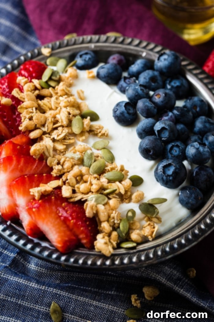 Creamy Instant Pot Yogurt 3 Bowl of instant pot yogurt with fresh blueberries, strawberries, pepitas, granola and a drizzle of honey in a vintage bowl with blue and purple napkins.