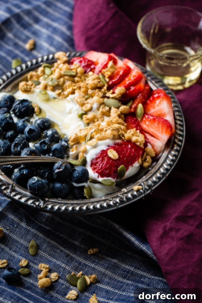 Creamy Instant Pot Yogurt 6 Instant pot yogurt in a vintage bowl with a drizzle of honey and granola with pepitas and fresh blueberries and sliced strawberries for a healthy breakfast recipe