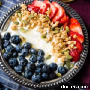 Instant pot homemade yogurt in a vintage bowl with a drizzle of honey and granola with pepitas and fresh blueberries and sliced strawberries for a healthy breakfast recipe