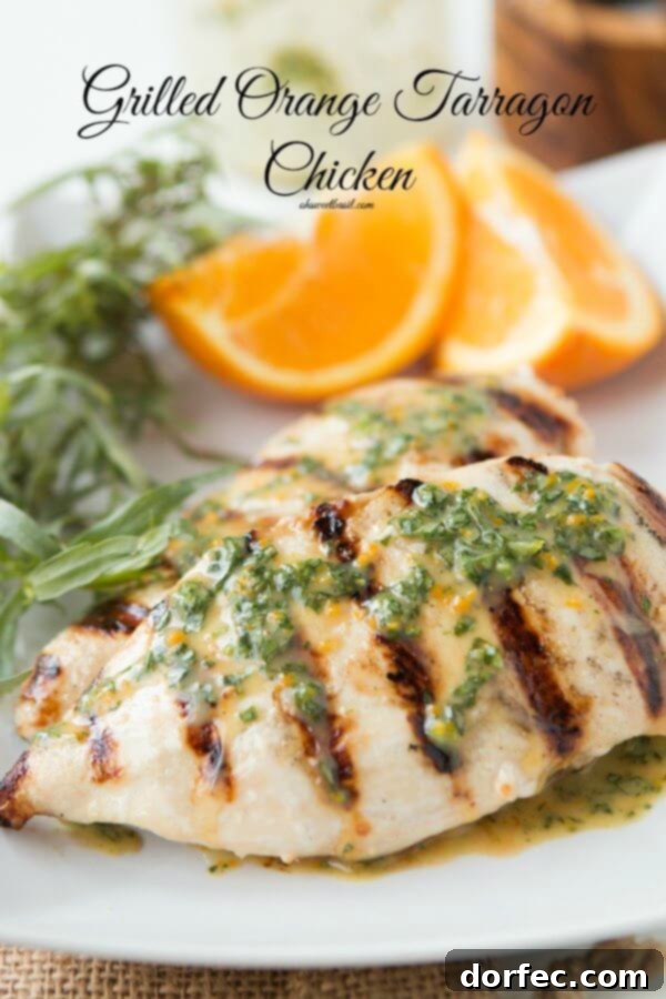 Close-up of a grilled orange tarragon chicken breast, garnished with fresh tarragon leaves, showcasing its juicy tenderness and vibrant flavor.
